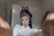 © TrueShot | Westend61 - Woman taking a skincare selfie with facial mask in bathroom