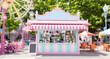 © Dimas - Vibrant carnival kiosk in sunny amusement park setting