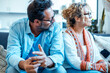 © simona - Middle-aged couple sitting apart on sofa after argument in cozy living room at home