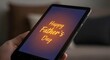 © MasoomBox - Close-up of a hand holding a tablet displaying Happy Father's Day message