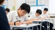 © Fahmy - East Asian Students Writing Exam in a Classroom Environment