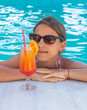 © yanadjan - Woman in the pool with a cocktail. Selective focus.