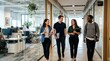 © UnPhouvith - Three smiling colleagues walk together down a modern office hallway. They are holding a document and appear to be engaged in a casual conversation.