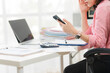 © Wicitr - Workplace Phone Interaction: An individual in a professional environment, engrossed in a mobile phone, signifying modern business communication and potential work-related interactions.