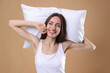 © New Africa - Beautiful woman with pillow on beige background