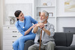 © New Africa - Care worker supporting senior man with walking cane indoors
