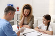 © New Africa - Endocrinologist consulting woman with her daughter and showing models of thyroid glands at white desk in clinic
