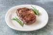 © alex9500 - Perfectly grilled beef steak with rosemary on white plate premium restaurant presentation