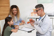 © New Africa - Endocrinologist in glasses consulting woman with her daughter and showing model of thyroid gland at white desk in clinic