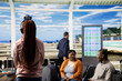 © DC Studio - Teen listens to music, black girl with headphones, waiting for vacation flight, busy departure area at the airport terminal. Solo traveler waiting impatiently for boarding plane in lounge.