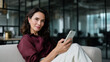 © Helga - Businesswoman Checking Smartphone on Sofa in Contemporary Office, Modern Female Executive, Corporate Lounge Lifestyle, Mobile Communication and Workplace Technology Concept a profe