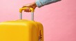 © oksa_studio - Unrecognizable person's hand holding the extendable handle of a bright yellow suitcase, symbolizing travel, vacation, and adventure