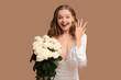 © Pixel-Shot - Happy young woman with engagement ring and bouquet of white roses on beige background