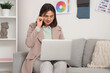 © Pixel-Shot - Beautiful interior designer working with laptop on sofa in office