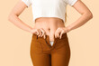 © Pixel-Shot - Young woman in tight pants on beige background, closeup. Weight gain concept