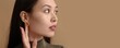 © Pixel-Shot - Young Asian woman wearing beautiful earrings on beige background with space for text