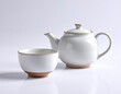 © Boedie - Minimalist white ceramic teapot and matching teacup set, featuring warm natural brown bases, elegantly presented on a bright reflective surface for a tranquil tea ritual