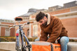 © Oscar - Courier man checking order on delivery bicycle