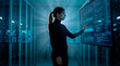 © Rendara Studio - Data engineer woman reviewing analytics dashboards on large screen inside datacenter corridor