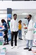 © DC Studio - Healthcare worker recommending vitamin C supplements to a young man, assisting with medication instructions and advice at the pharmacy. Professional pharmaceutical service for wellness.