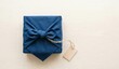 © 正行 髙橋 - Top view flat lay of a gift neatly wrapped in a traditional Japanese Furoshiki cloth on a bright wooden table