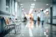 © cita - Blurred hospital hallway with waiting chairs on the left and two people in scrubs walking away