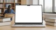 © Neo - Sleek laptop with an empty white screen sits on a wooden table surrounded by hardcover books in a bright, modern library setting with soft natural light product mockup design