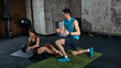© master1305 - Fitness trainer instructing woman during seated core rotation exercise with medicine ball. Concept of functional training, technique coaching, core stability and fitness progression