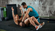 © master1305 - Woman doing abdominal crunch exercise on mat with male coach support in gym. Concept of core training routine, injury prevention, fitness guidance and healthy lifestyle habit