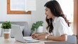 © Fatin - Focused young woman working remotely from home, actively engaged with her laptop and taking notes, reflecting modern flexible productivity and online learning