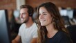 © Bussakon - A young professional woman smiles during a collaborative moment in a modern open plan office setting with colleagues