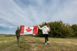 © Anna - Canadian flag held by people walking in nature. Happy Canada Day. Pride, freedom, patriotism. Traveling across the country. National symbol. Mom with children.