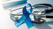 © Irina Kado - Blue ribbon beside stethoscope lying on a white background. Men health awareness month and prostate cancer prevention campaigns.