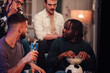 © Zamrznuti tonovi - Group of diverse male friends sharing popcorn and drinks, watching a soccer match on tv in a cozy living room at night