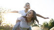 © My Ocean studio - Smiling mother giving her son a piggyback ride outdoors, playful family moment, child pretending to fly, summer fun and Mother’s Day concept.