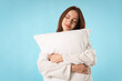 © New Africa - Beautiful woman with pillow on light blue background. Space for text