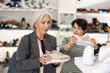 © JackF - Two women are shopping in shoe store and young colleague shows elderly lady advantages of thick sole in modern snickers. Female clients choose jogging shoes