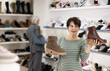 © JackF - Adult female shopper purchases warm boots in shoe store