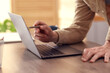 © New Africa - Man with pen near laptop at wooden desk in office, closeup