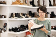 © JackF - While shopping, woman takes samples from showcase and examines shoes. Client thinks about it and makes purchase decision, inquires about price.