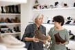 © JackF - Elderly and adult female customers purchases pair of boots in shoe store