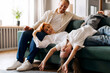 © Home-stock - Excited family of three relaxing on comfortable couch, sharing joyful moments, girl playfully hanging upside down, parents smiling