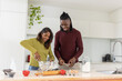 © wavebreak3 - Indian woman and African American man preparing batter at kitchen island with glass bowl and eggs