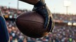 © Andrey - Close-up of a gloved hand gripping a football during an NFL draft event, with a blurred stadium crowd in the background under bright stadium lights