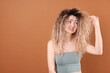© New Africa - Unhappy woman with tangled damaged hair on brown background, space for text