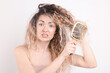 © New Africa - Unhappy woman trying to brush her tangled hair on light grey background
