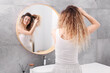 © New Africa - Unhappy woman trying to brush her tangled hair near mirror in bathroom