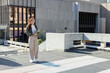 © wavebreak3 - Woman standing on left terrace holding notes, wearing olive jacket and white sneakers, copy space