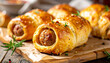 © hardvicore - Golden baked sausage rolls with fresh rosemary, rustic presentation, tasty food, cozy homemade snack, appetizing meal.