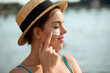 © verona_studio - Beautiful woman applying cream sunscreen on a tanned face. Sunscreen. Skin and body care. The girl uses a sunscreen for her skin. Portrait of a female holding suntan lotion and moisturizing sunscree